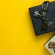 a black gift box with a gold ribbon on a yellow background