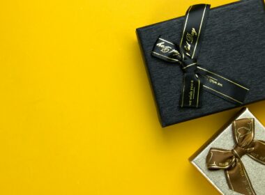 a black gift box with a gold ribbon on a yellow background