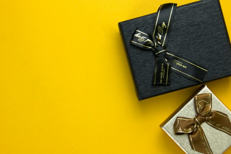 a black gift box with a gold ribbon on a yellow background